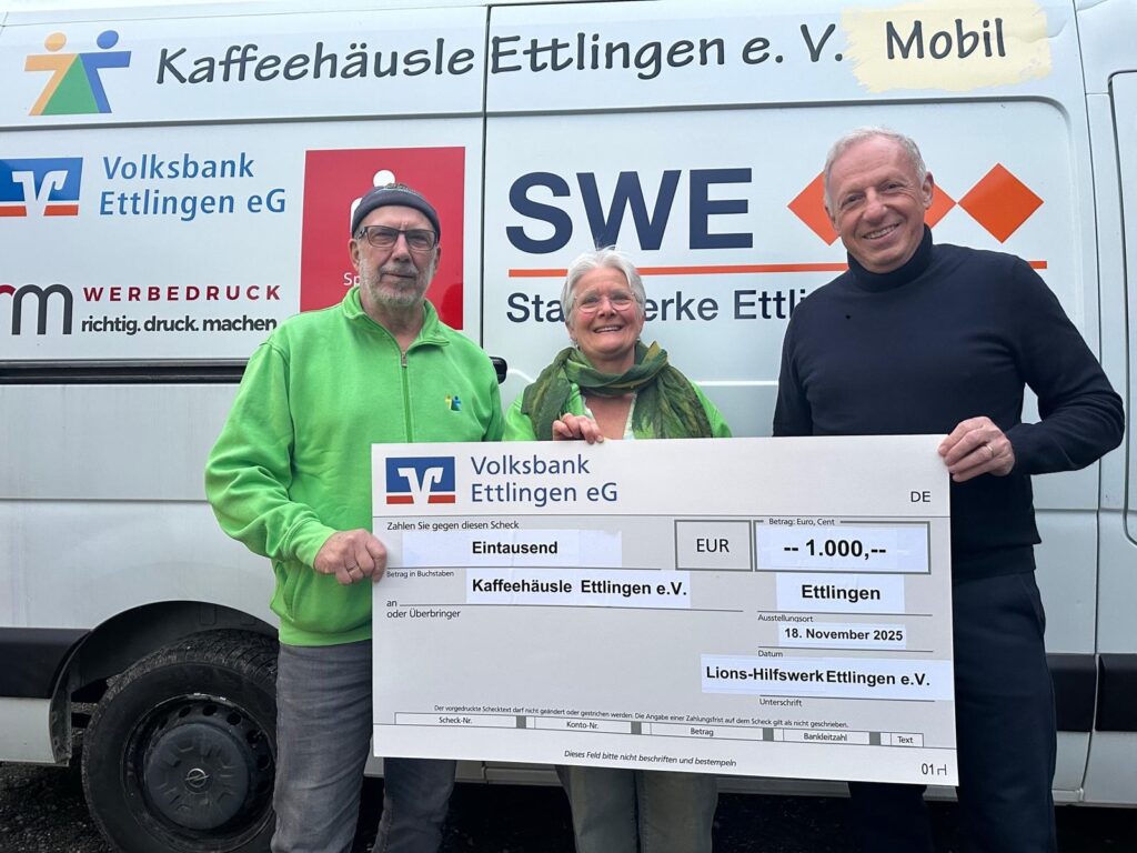 3 Personen lächeln bei der Spendenübergabe in die Kamera